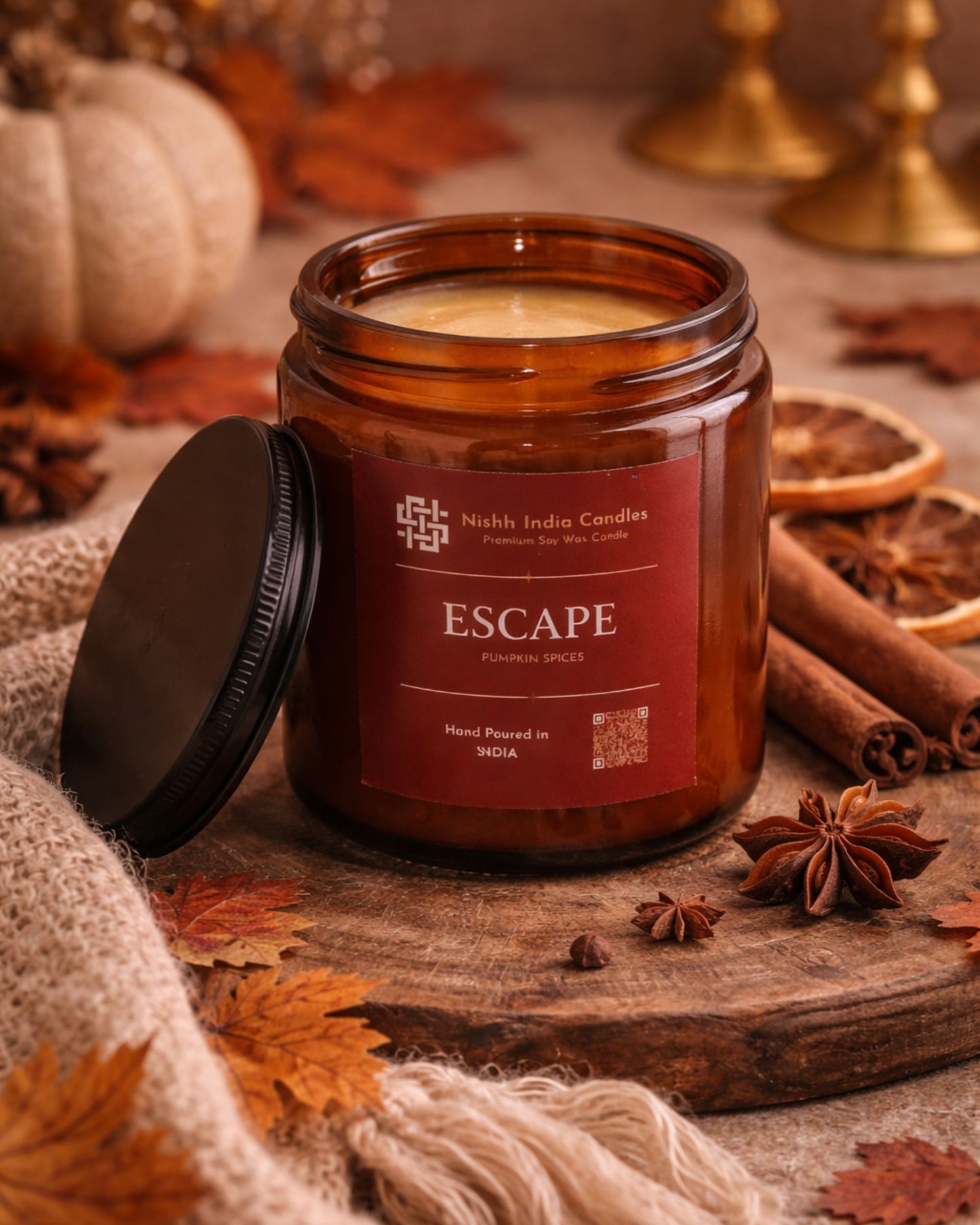 Fall Pumpkin Spice candle by Nishh India Candles styled in a cozy home setting with autumn leaves, soft knit fabric and warm lighting.