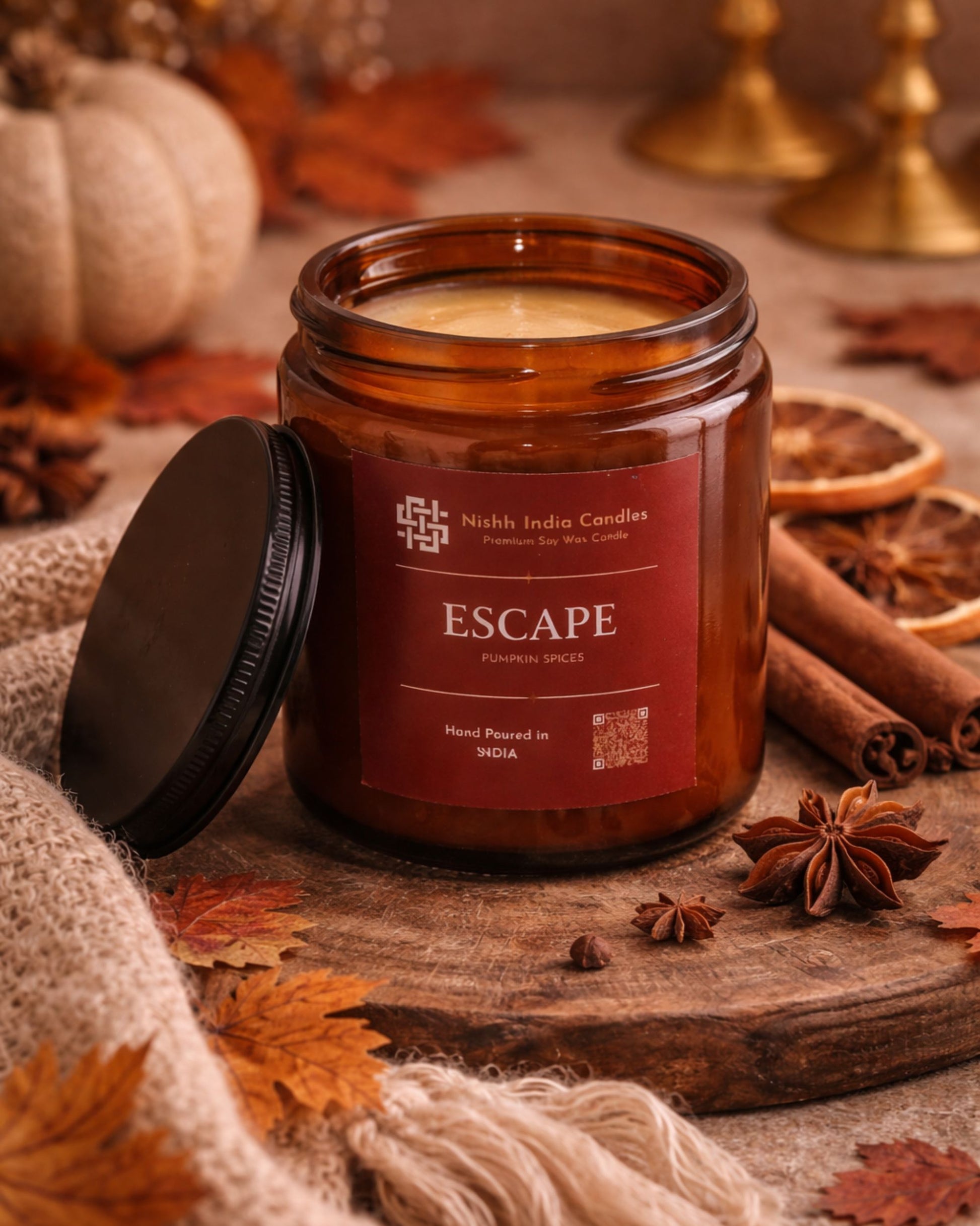 Fall Pumpkin Spice candle by Nishh India Candles styled in a cozy home setting with autumn leaves, soft knit fabric and warm lighting.