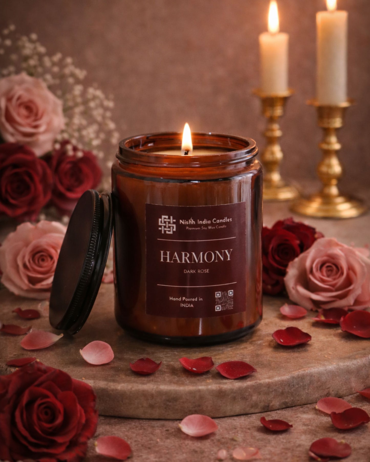 Lit dark rose scented soy candle in amber glass jar creating warm cozy evening ambience and relaxing romantic atmosphere.