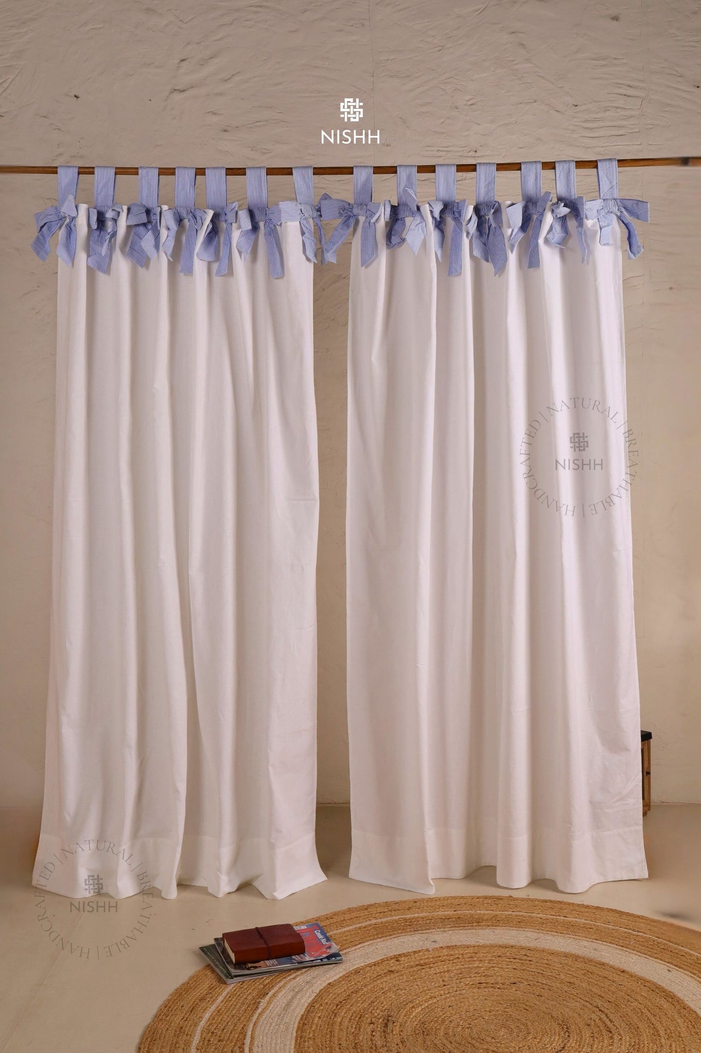 White curtains with blue ribbon ties on a wooden rod, tabtop hanging