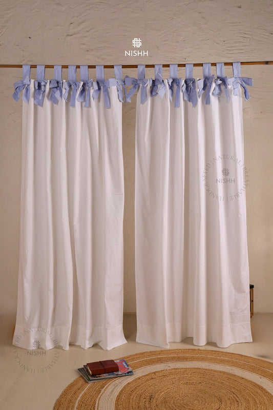 White curtains with blue ribbon ties on a wooden rod, tabtop hanging