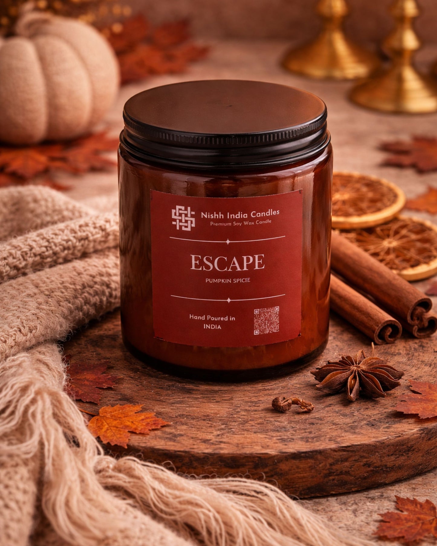 Pumpkin Spice soy wax candle in amber glass jar styled in a luxury autumn home decor setup with cinnamon sticks, dried orange slices and warm neutral tones.