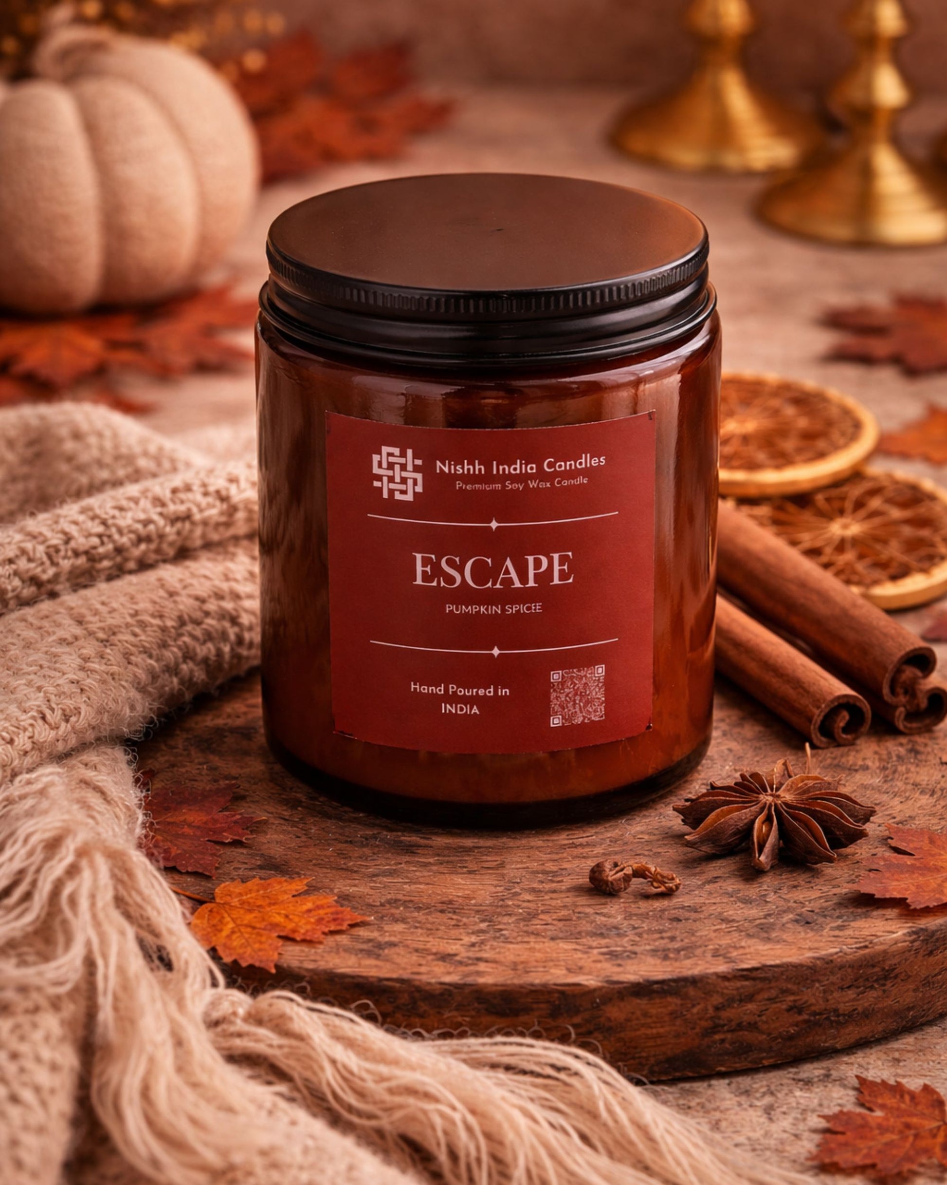 Pumpkin Spice soy wax candle in amber glass jar styled in a luxury autumn home decor setup with cinnamon sticks, dried orange slices and warm neutral tones.