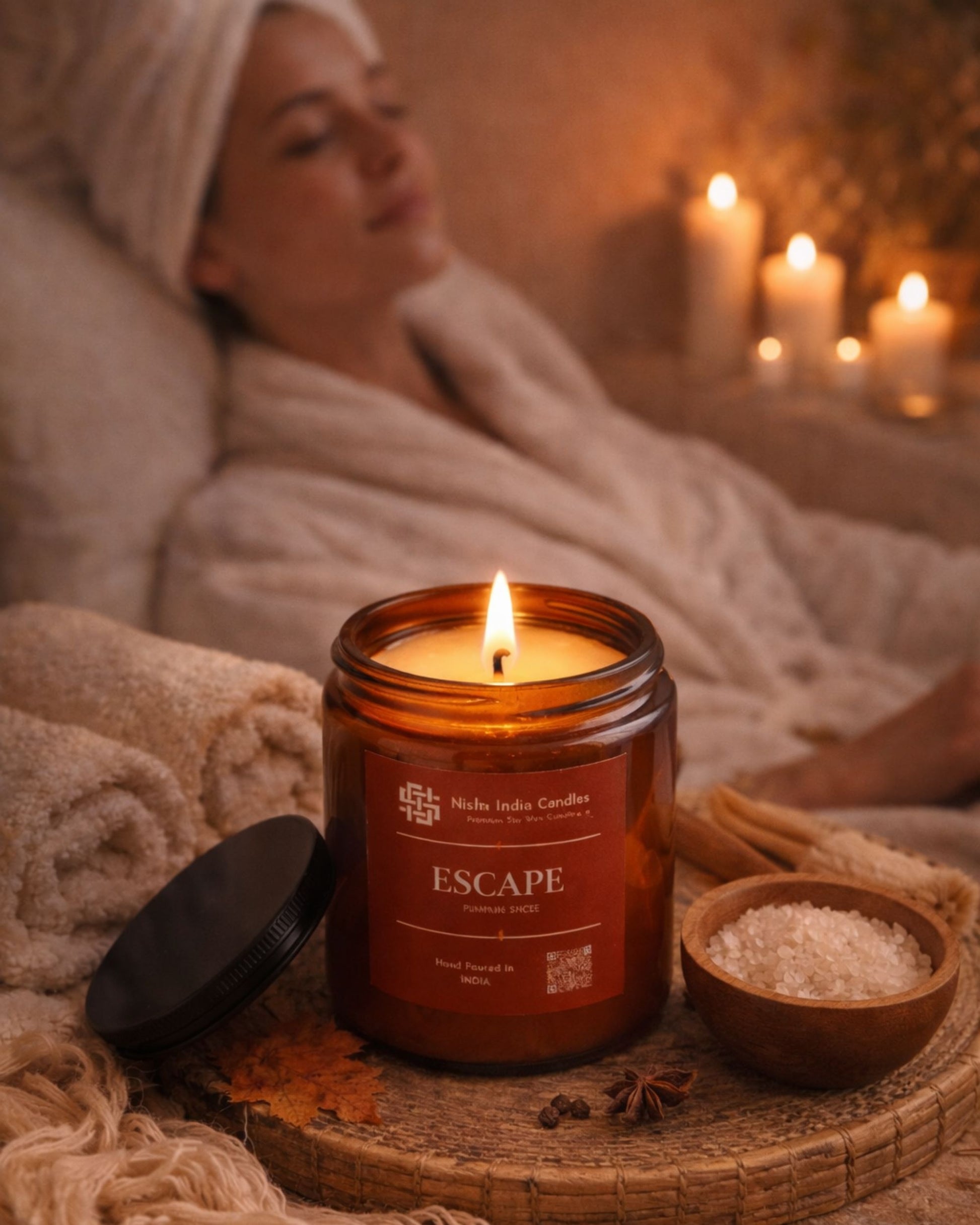 Fall Pumpkin Spice candle burning in amber jar creating a cozy evening ambience with warm tones, towels and relaxing spa decor.