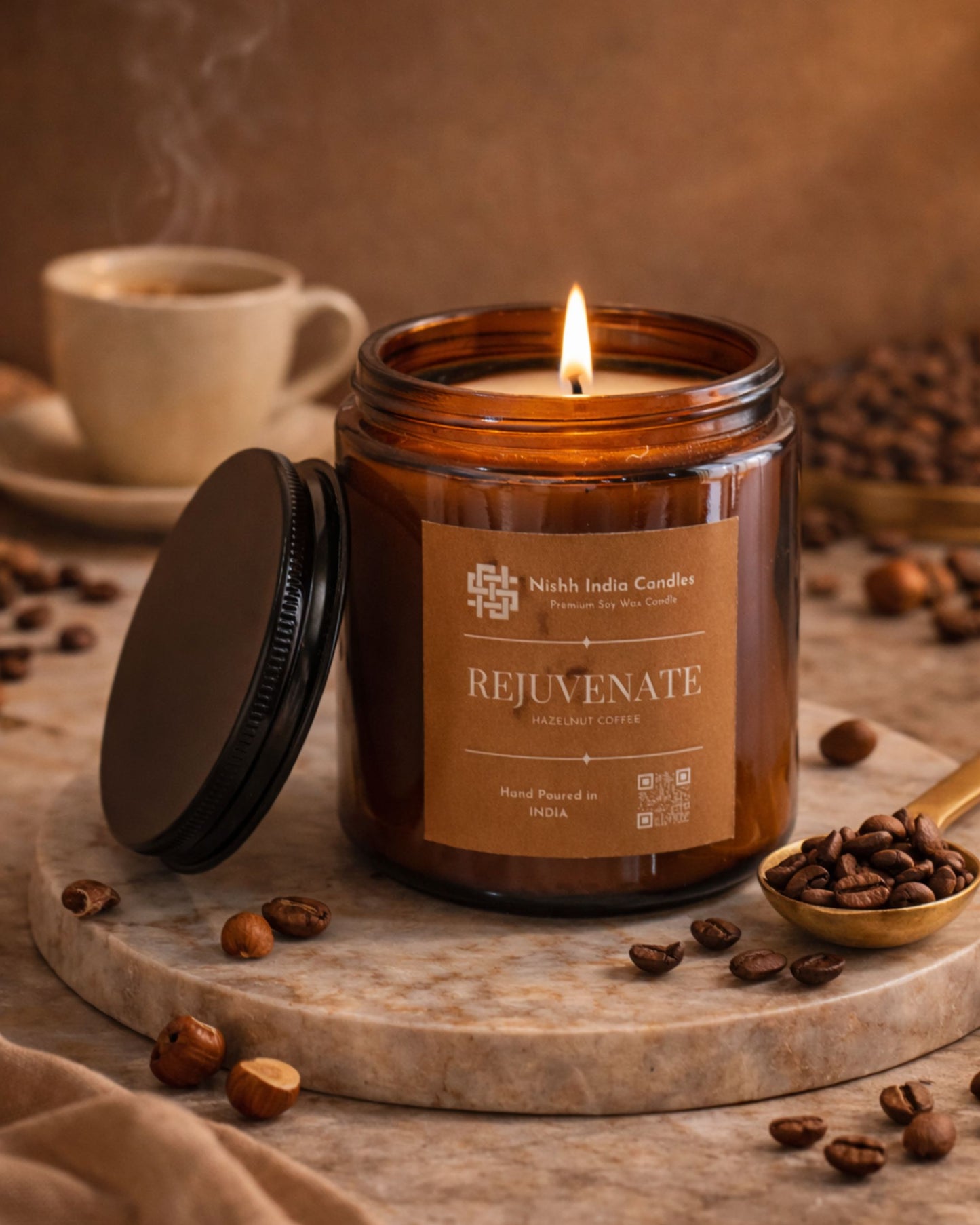 Luxury editorial setup of Nishh India Rejuvenate Hazelnut Coffee candle surrounded by roasted coffee beans and hazelnuts on marble surface