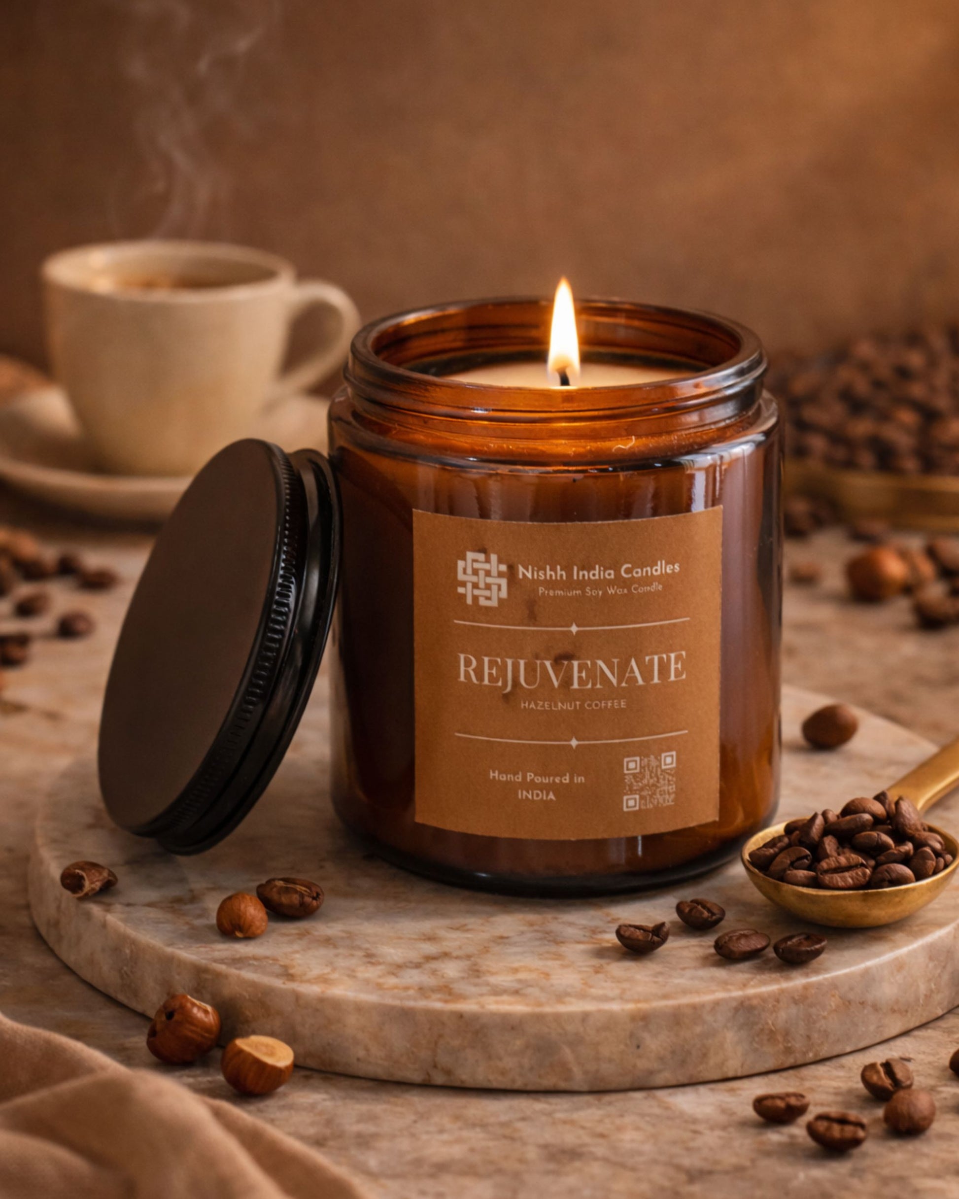 Luxury editorial setup of Nishh India Rejuvenate Hazelnut Coffee candle surrounded by roasted coffee beans and hazelnuts on marble surface