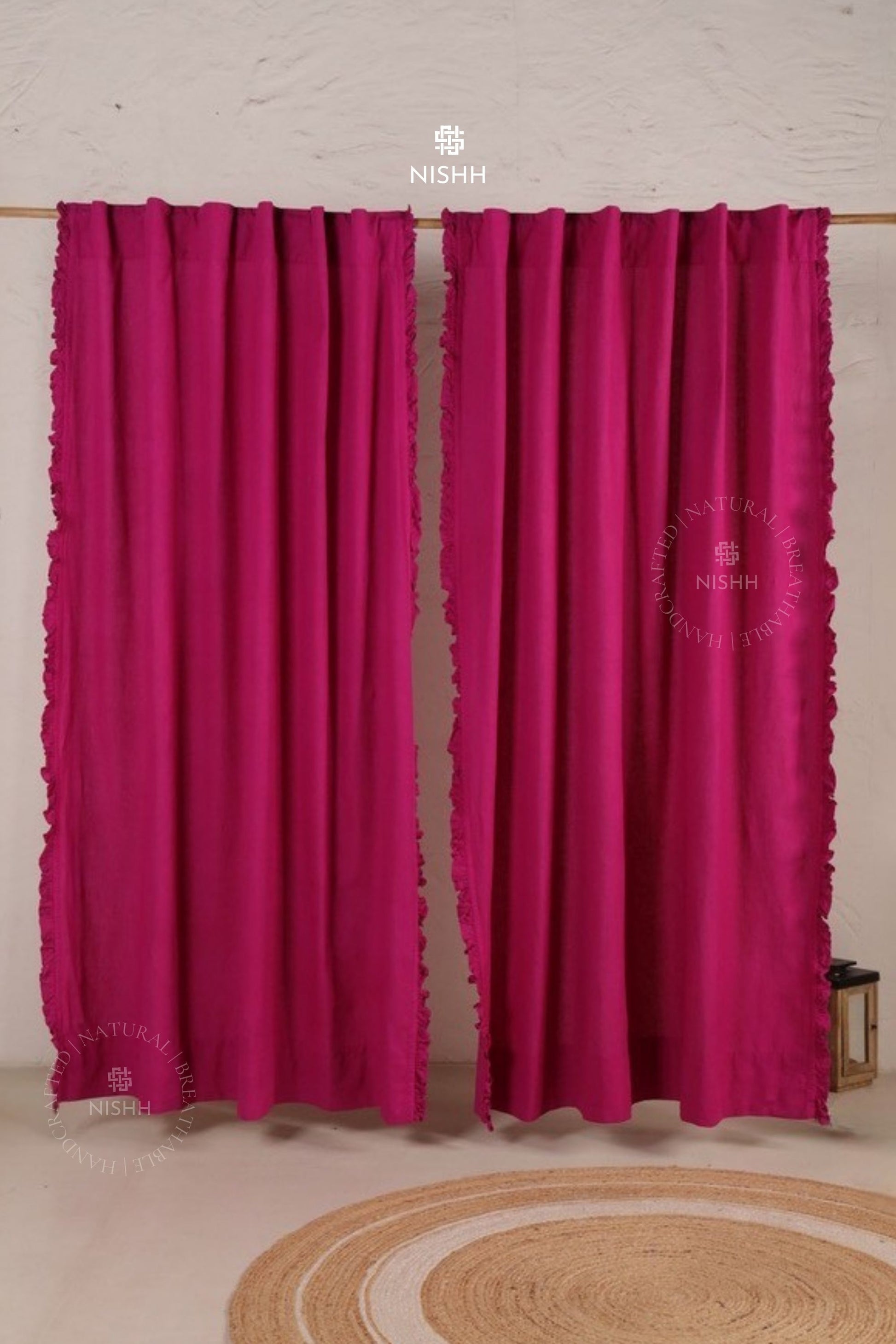 Pair of pink curtains with lace trim on a wooden rod against a light-colored wall.