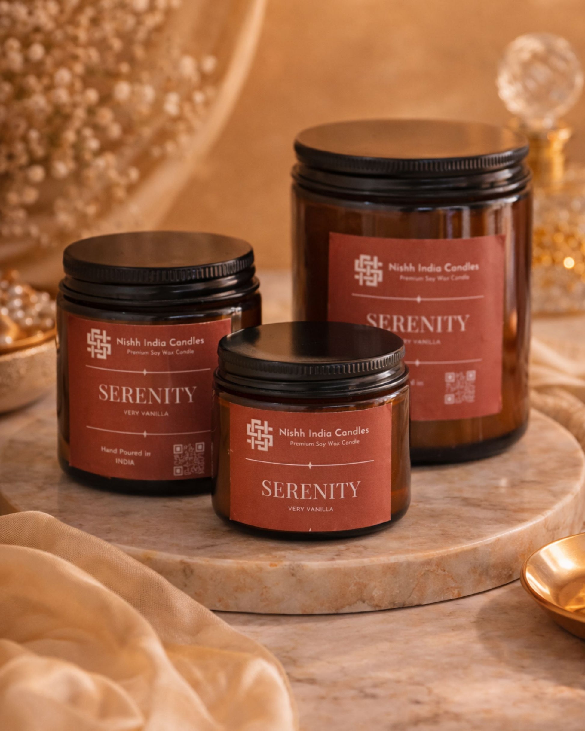 Serenity Very Vanilla amber jar soy candles by Nishh India in three sizes displayed on marble tray with warm luxury home decor styling.