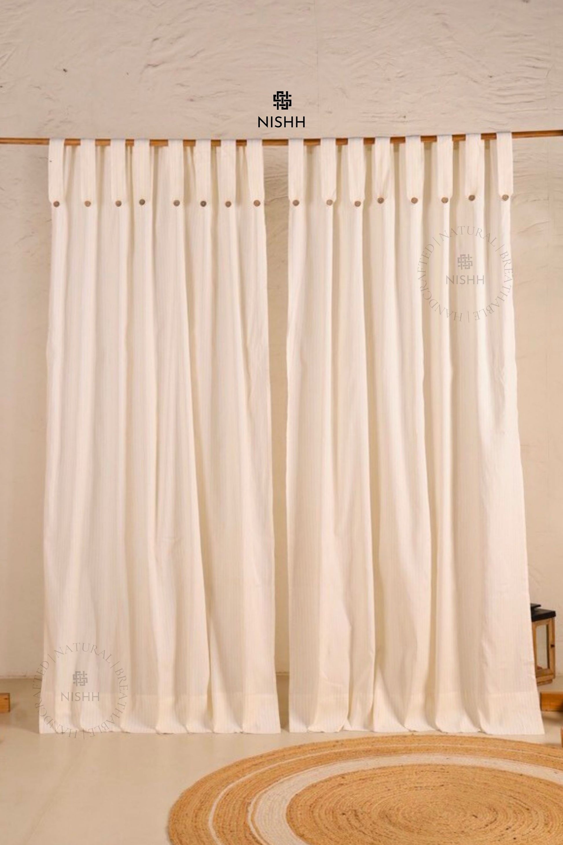 White curtains with wooden rod and 'NISHH' branding in a minimalistic room.
